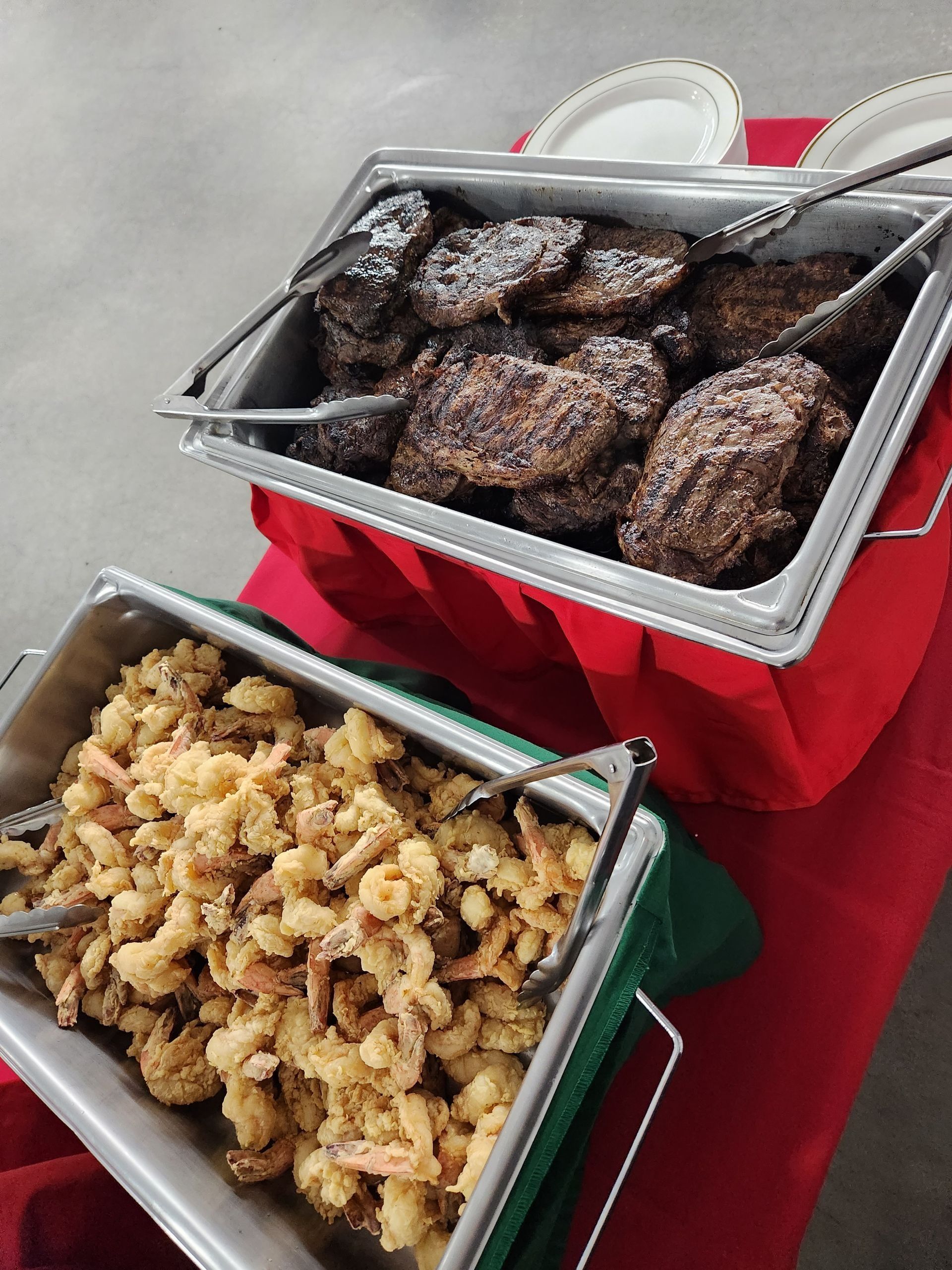 Two trays of food are on a table including hamburgers and macaroni and cheese.
