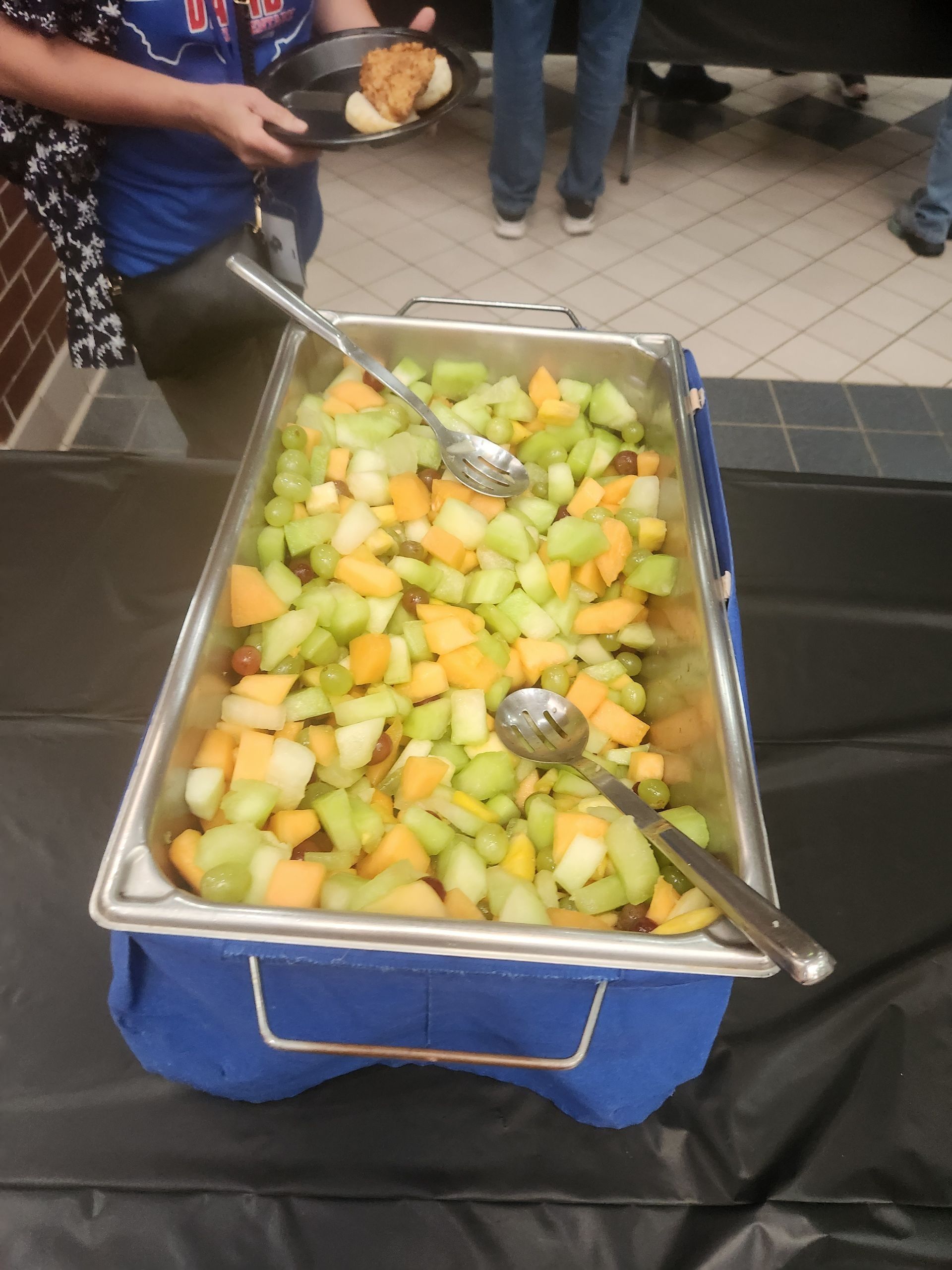 A tray of fruit with a spoon and fork in it