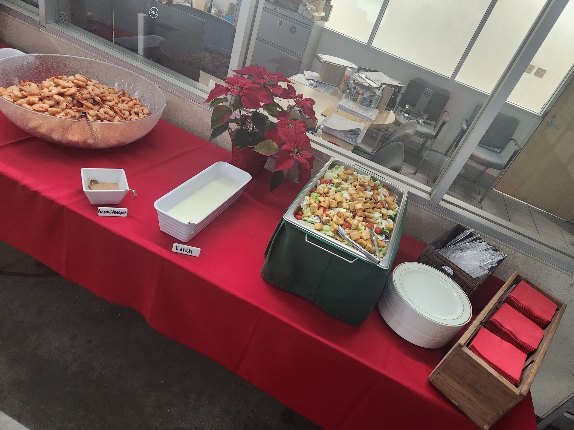 A table with a red table cloth and a variety of food on it.