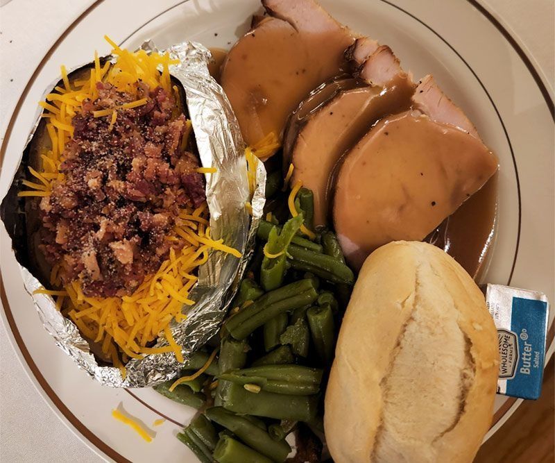 A plate of food with a baked potato green beans and gravy