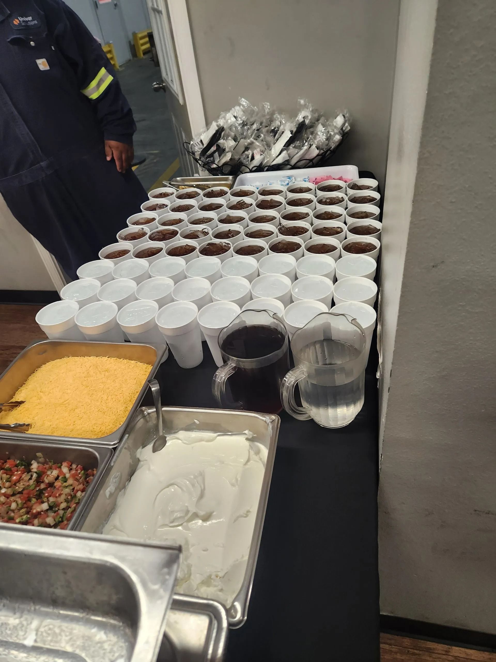 A table filled with lots of cups of coffee and a pitcher of water.