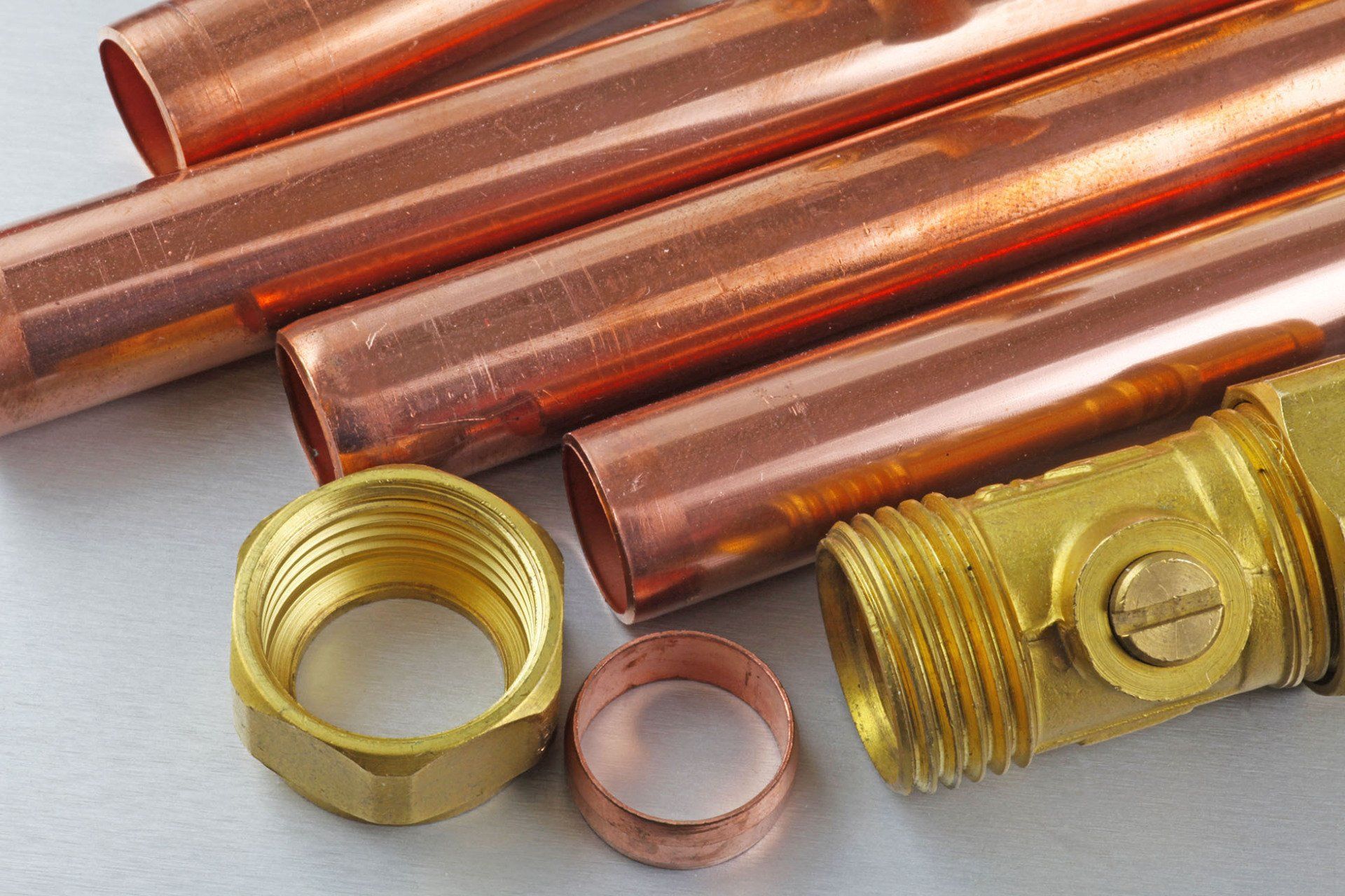 copper pipes and brass fittings are stacked on top of each other on a table .