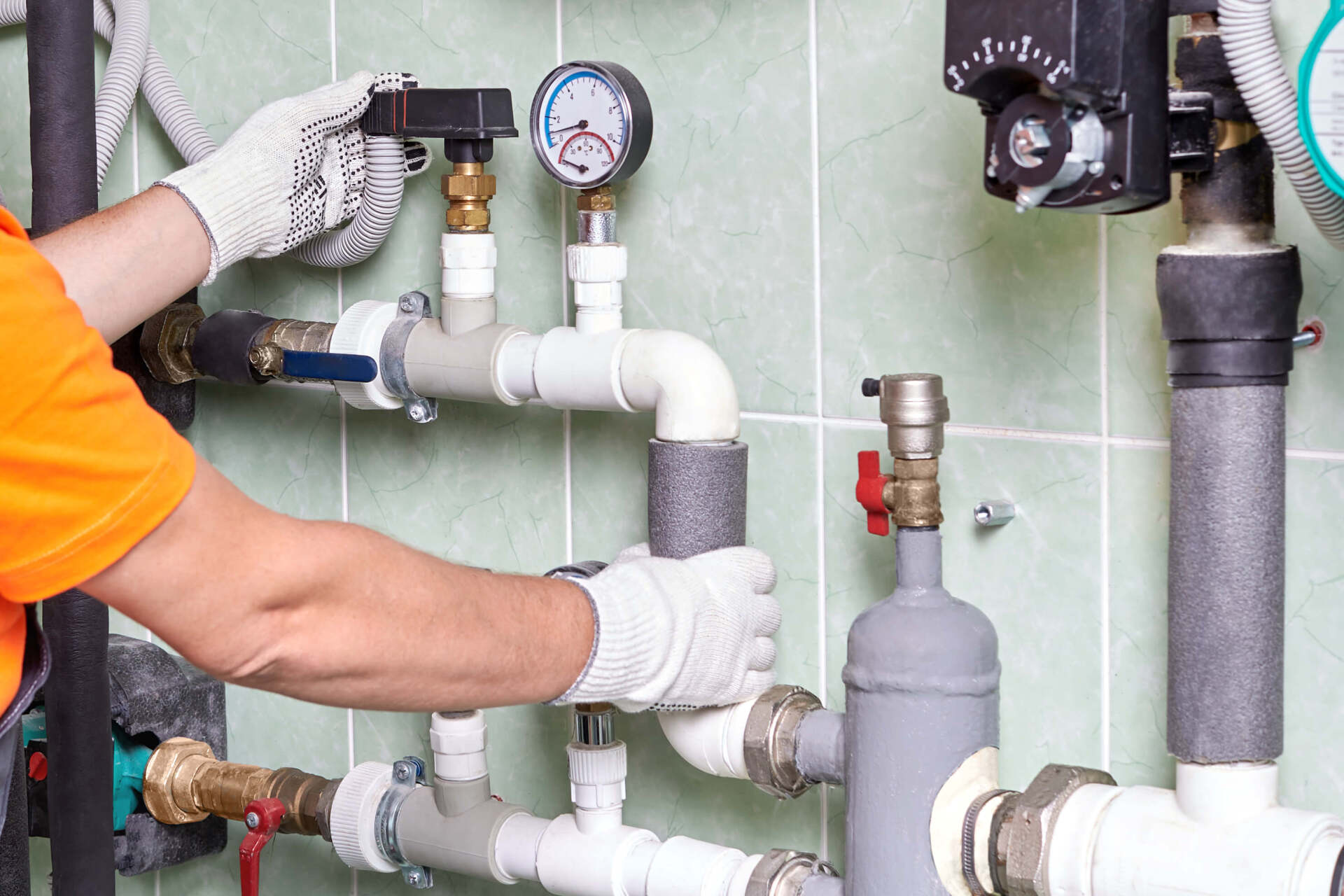 a man is working on a pipe system in a bathroom .
