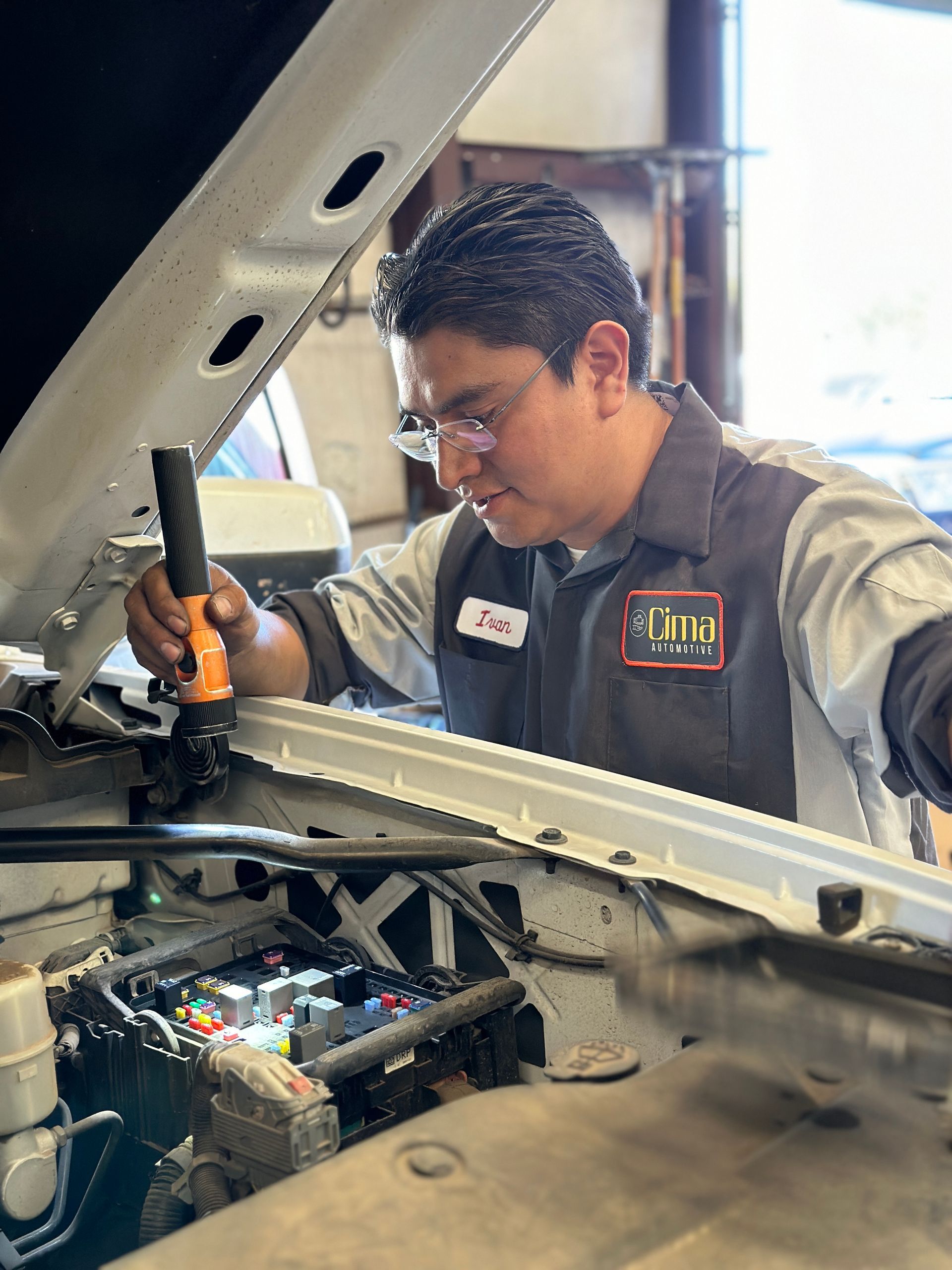 A man is working on a car with the hood open.