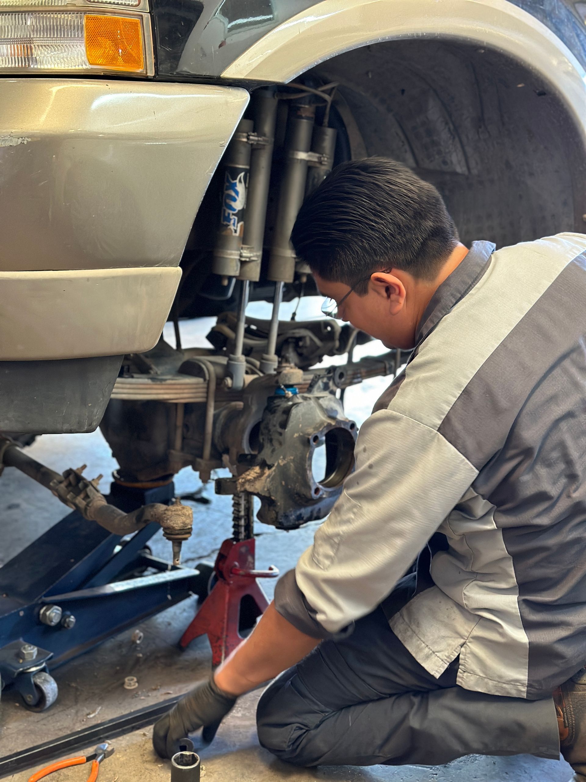 A man is working on the front of a car in a garage.
