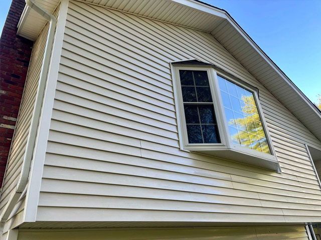 Beige siding on a house with a window, showing visible mold or mildew - after