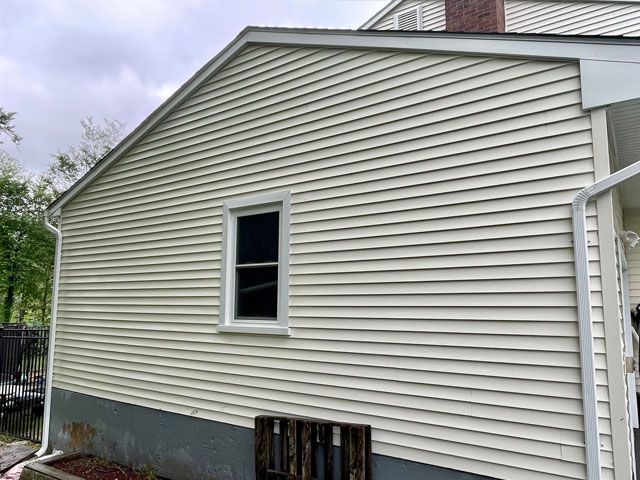 A house with dirty, green siding. A window is in the center. A wooden pallet rests below. - after