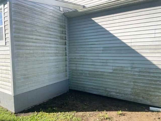 Exterior of a house with weathered siding; corner and lower portion exhibit green mildew. - before