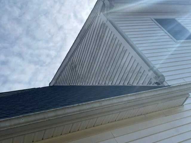 House exterior with white siding and dark roof under a cloudy sky - before