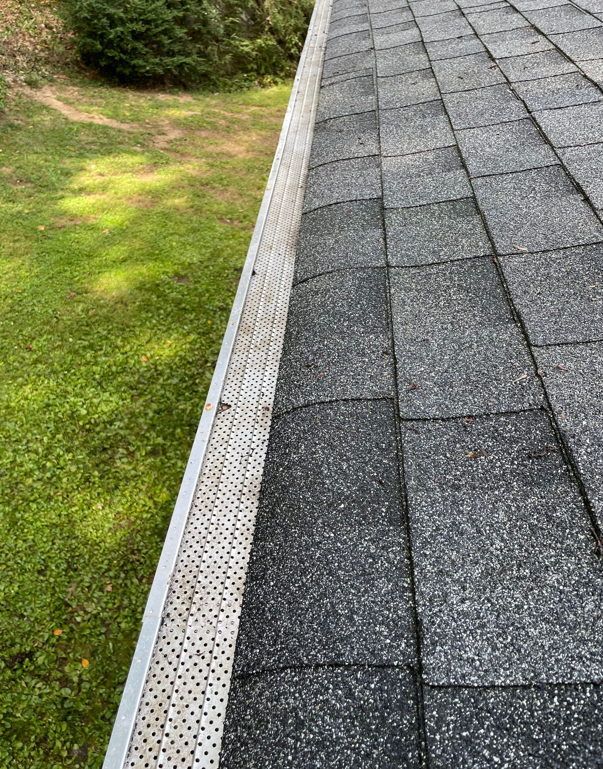 Roof with gutter guard next to green grass.