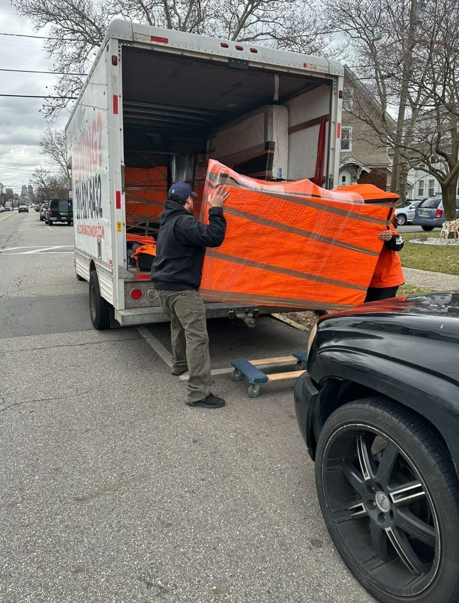 A man is loading a piano into a moving truck.