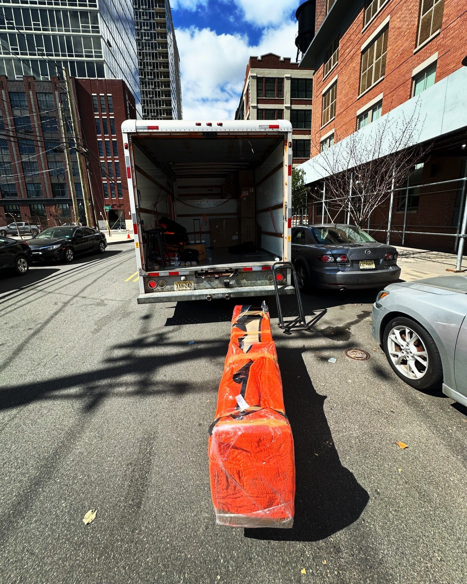 A gray car is parked in front of a moving truck