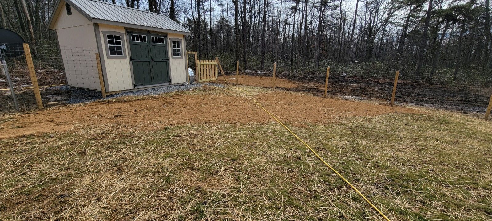 A shed is sitting in the middle of a grassy field.