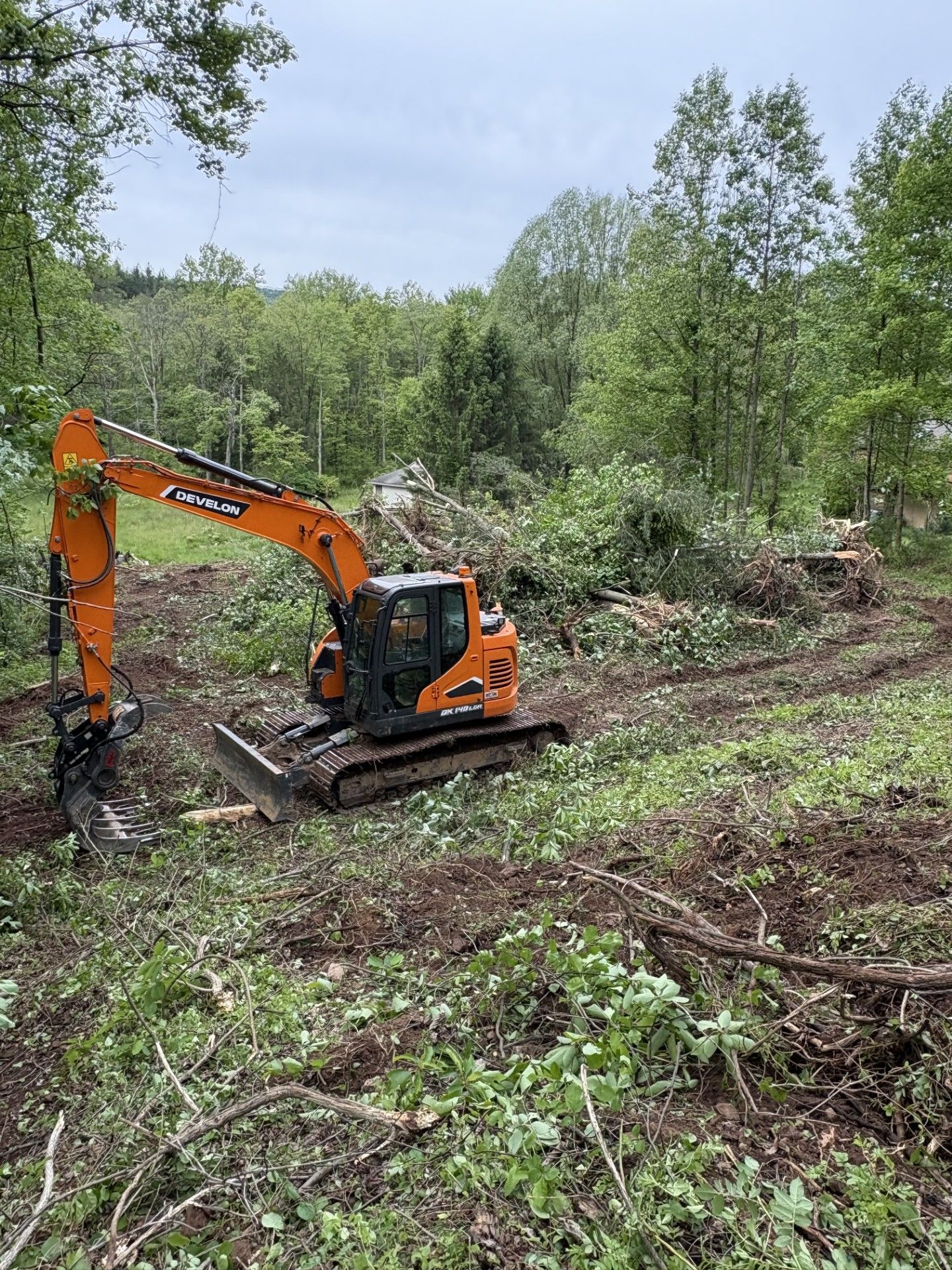 Two excavators are working in a field with trees in the background.