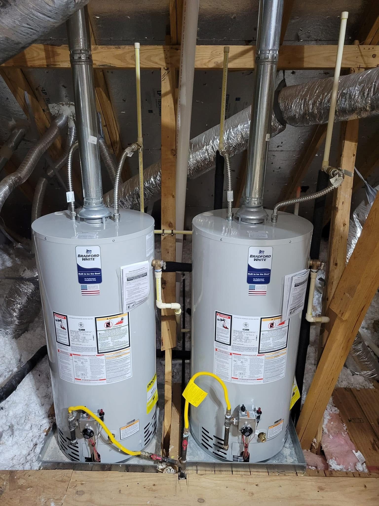Two water heaters side-by-side in an attic, with metal chimneys and yellow gas lines.