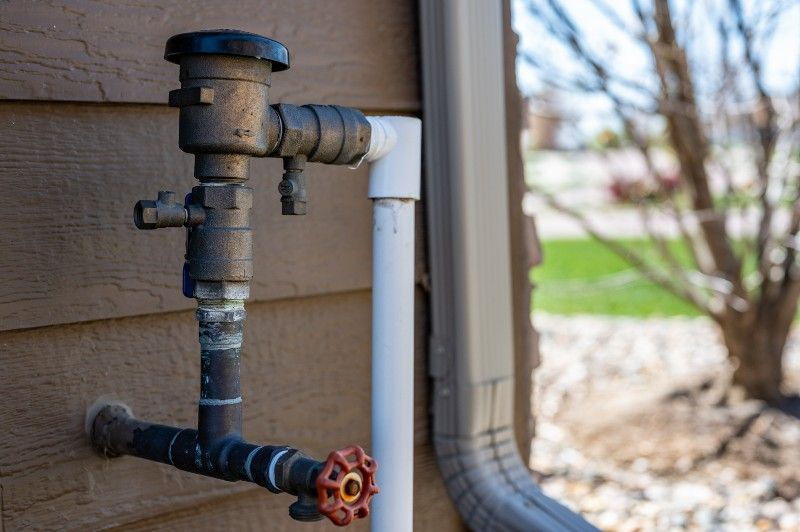 A close up of a backflow on the side of a house.