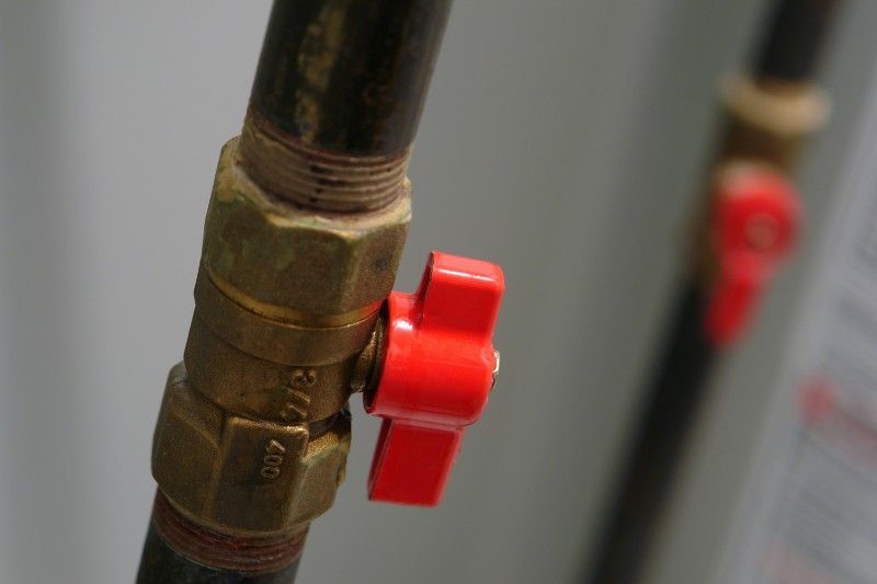 A close up of a red valve on a pipe.