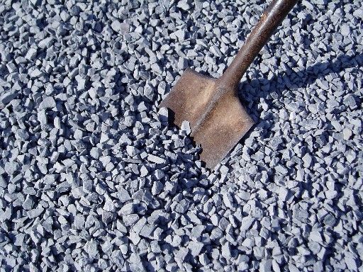 Gray gravel with a shovel partially buried in it.