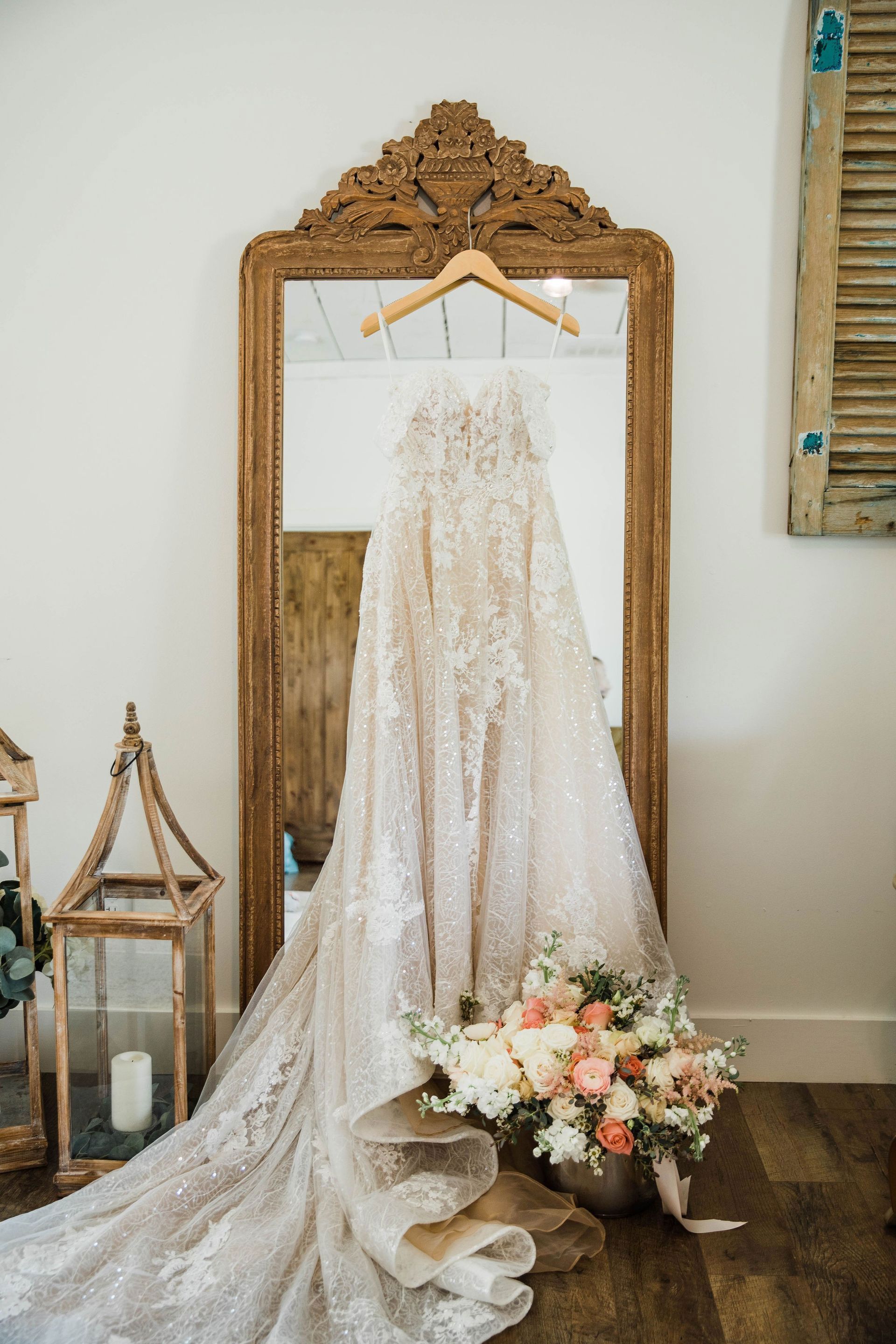 a wedding dress is hanging on a hanger in front of a mirror .