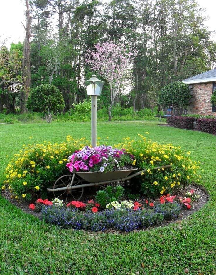 a wheelbarrow filled with flowers is in the middle of a garden