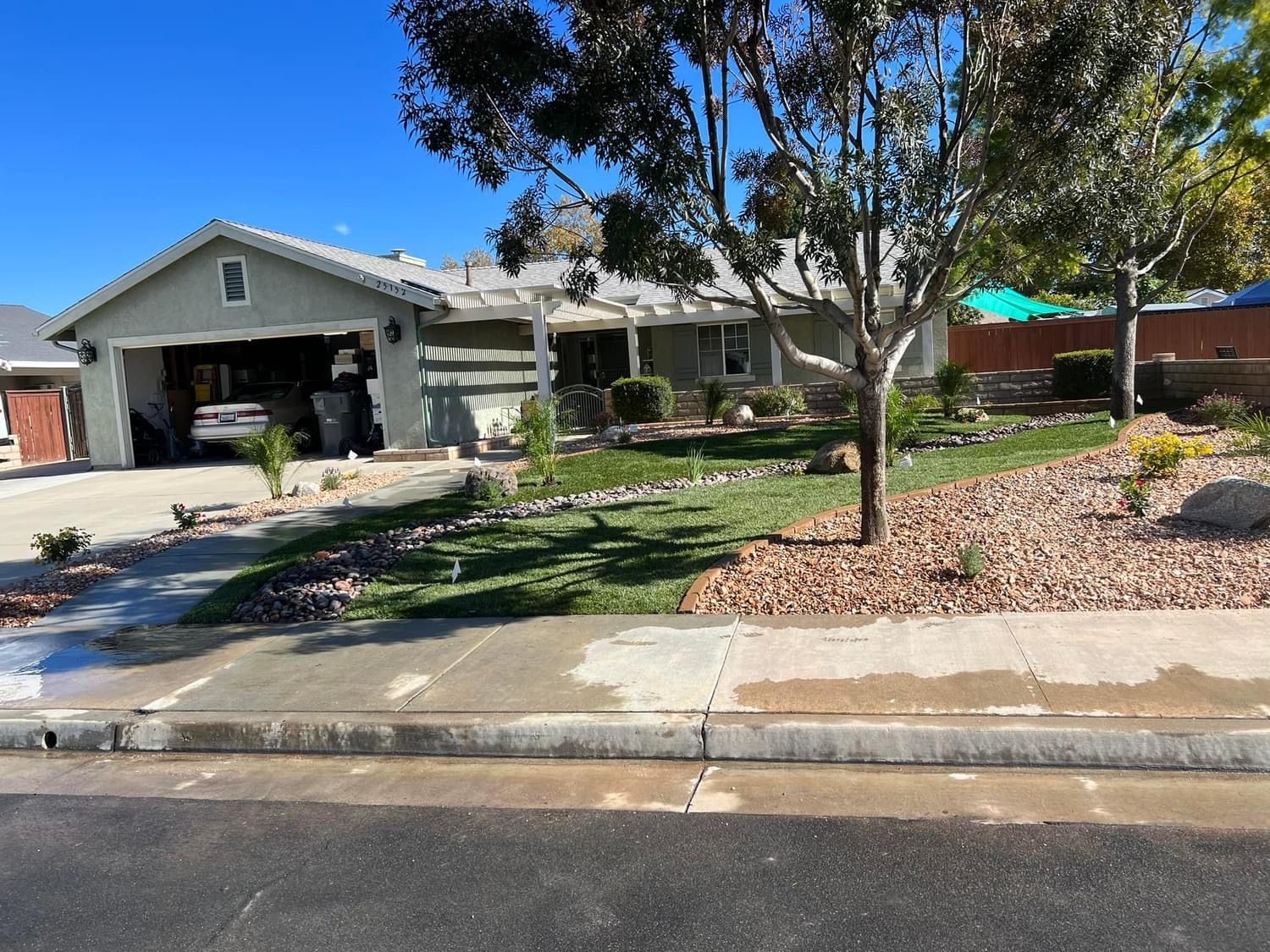 a house with a car parked in the driveway and a tree in front of it