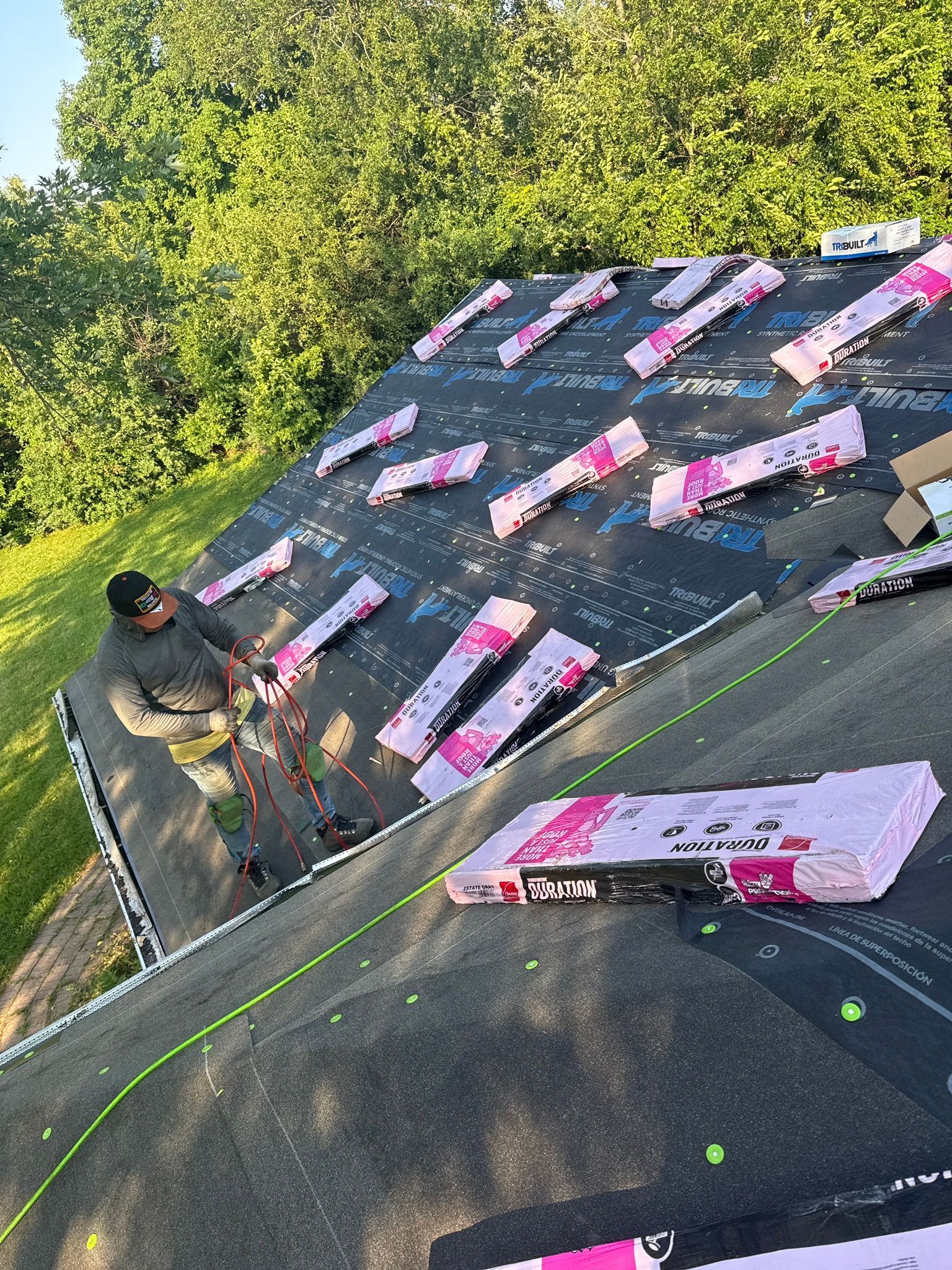 Roofer installing pink insulation panels on a roof covered with black underlayment.