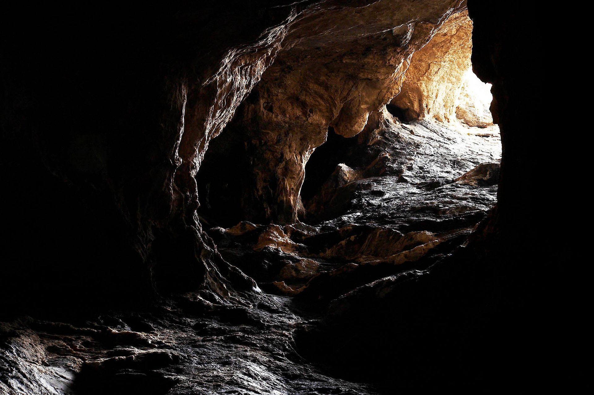 A dark cave with a light coming out of the end of it.