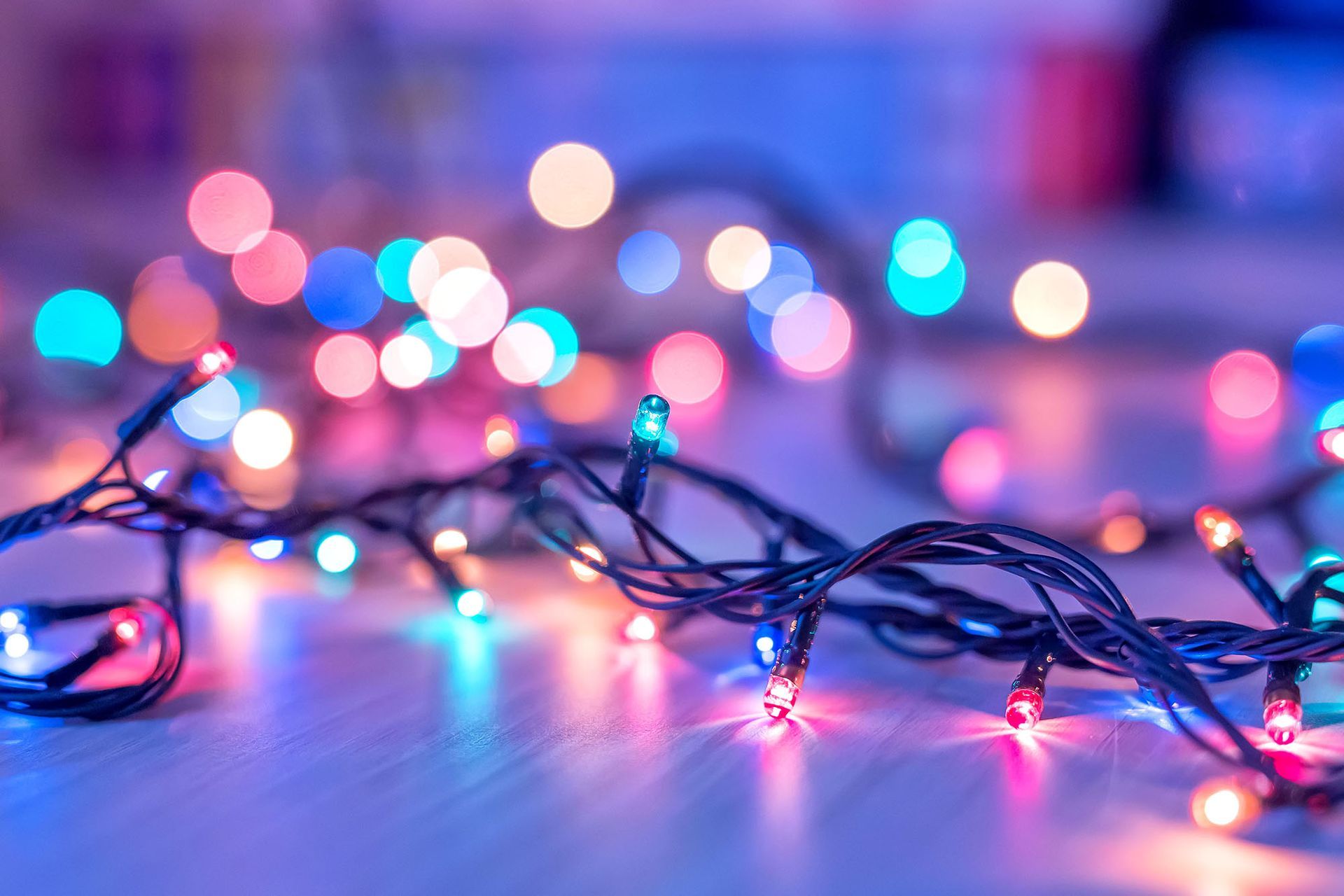 A close up of a string of colorful Christmas lights on a wooden floor.