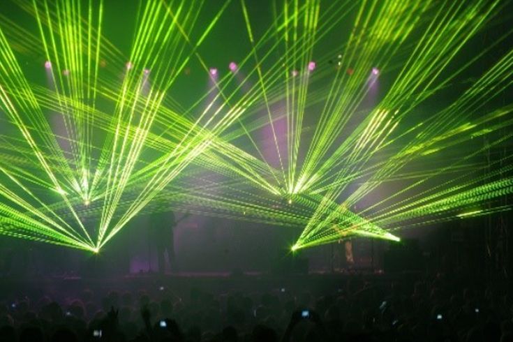A crowd of people watching a concert with green lights coming out of the ceiling