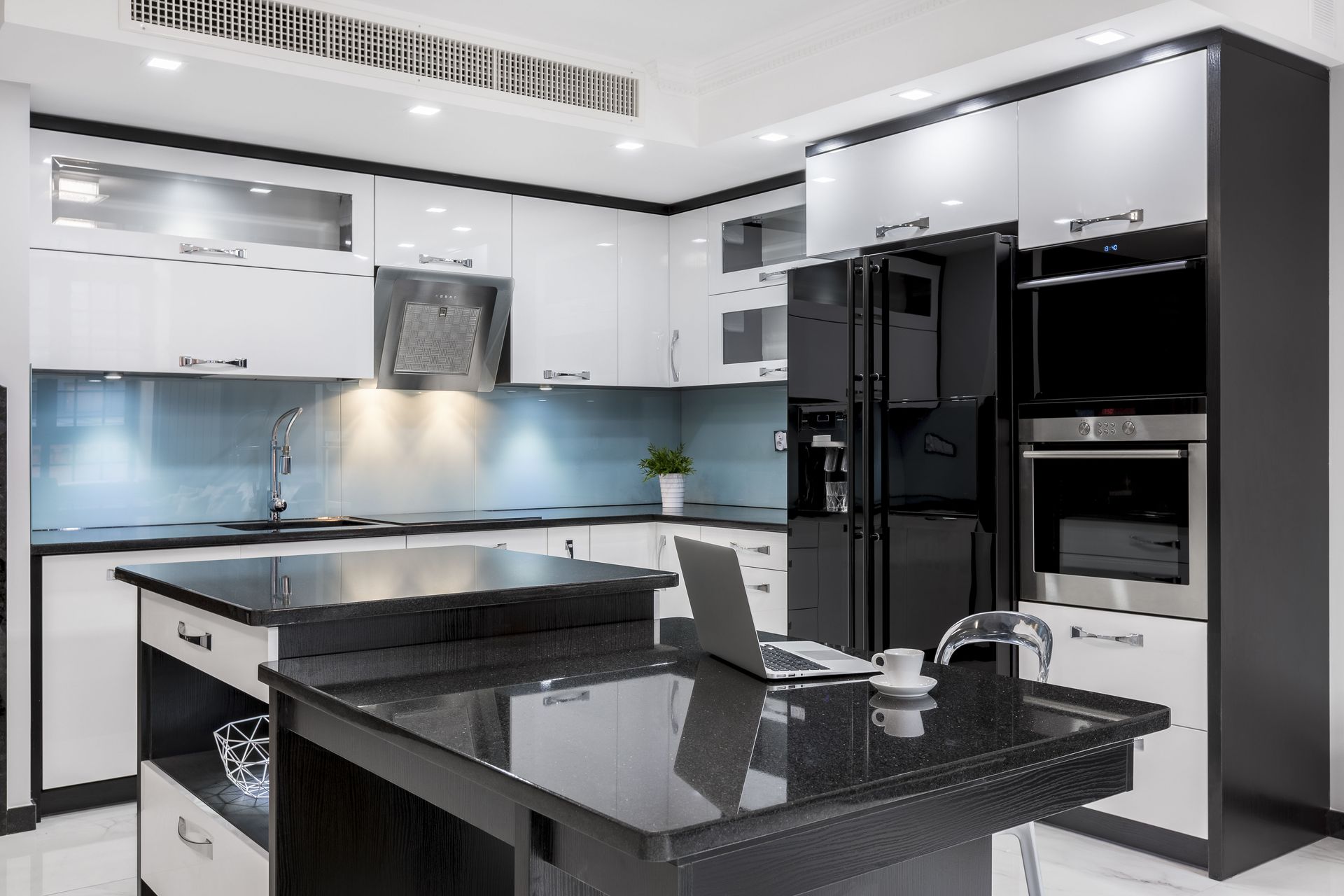 Modern black-and-white kitchen with glossy cabinets, island, and built-in appliances