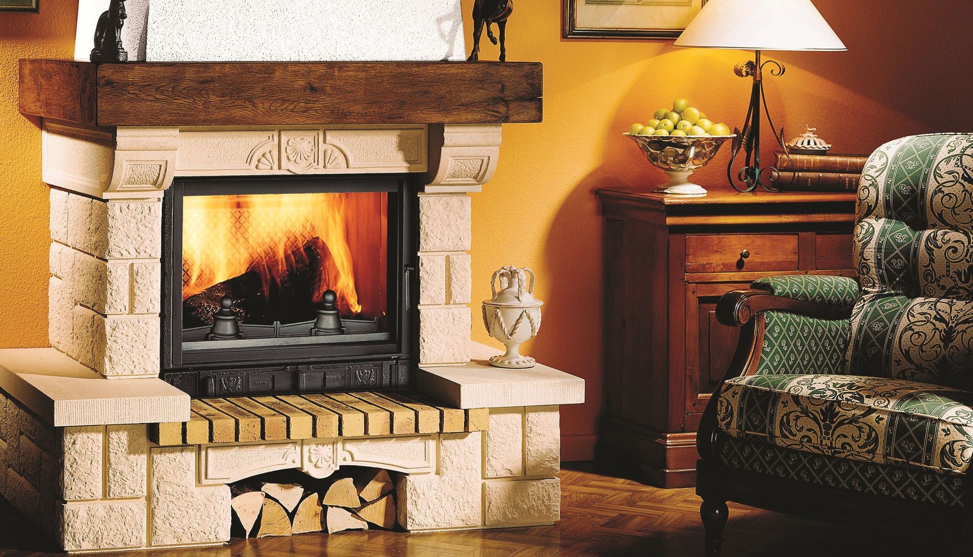 Cozy living room with a stone fireplace burning, lamp-lit side table, and patterned armchair