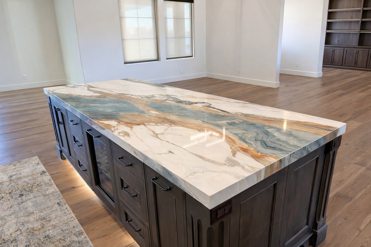 Large kitchen island with marble countertop and dark wood base in an empty room