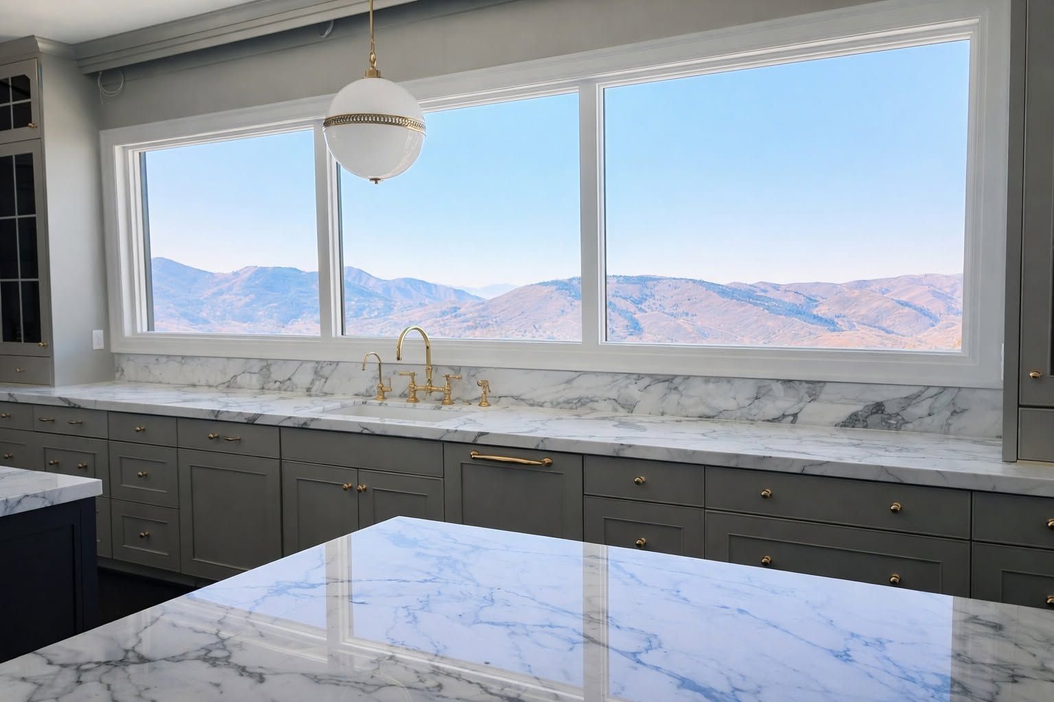 Modern kitchen with marble island and large windows overlooking mountains