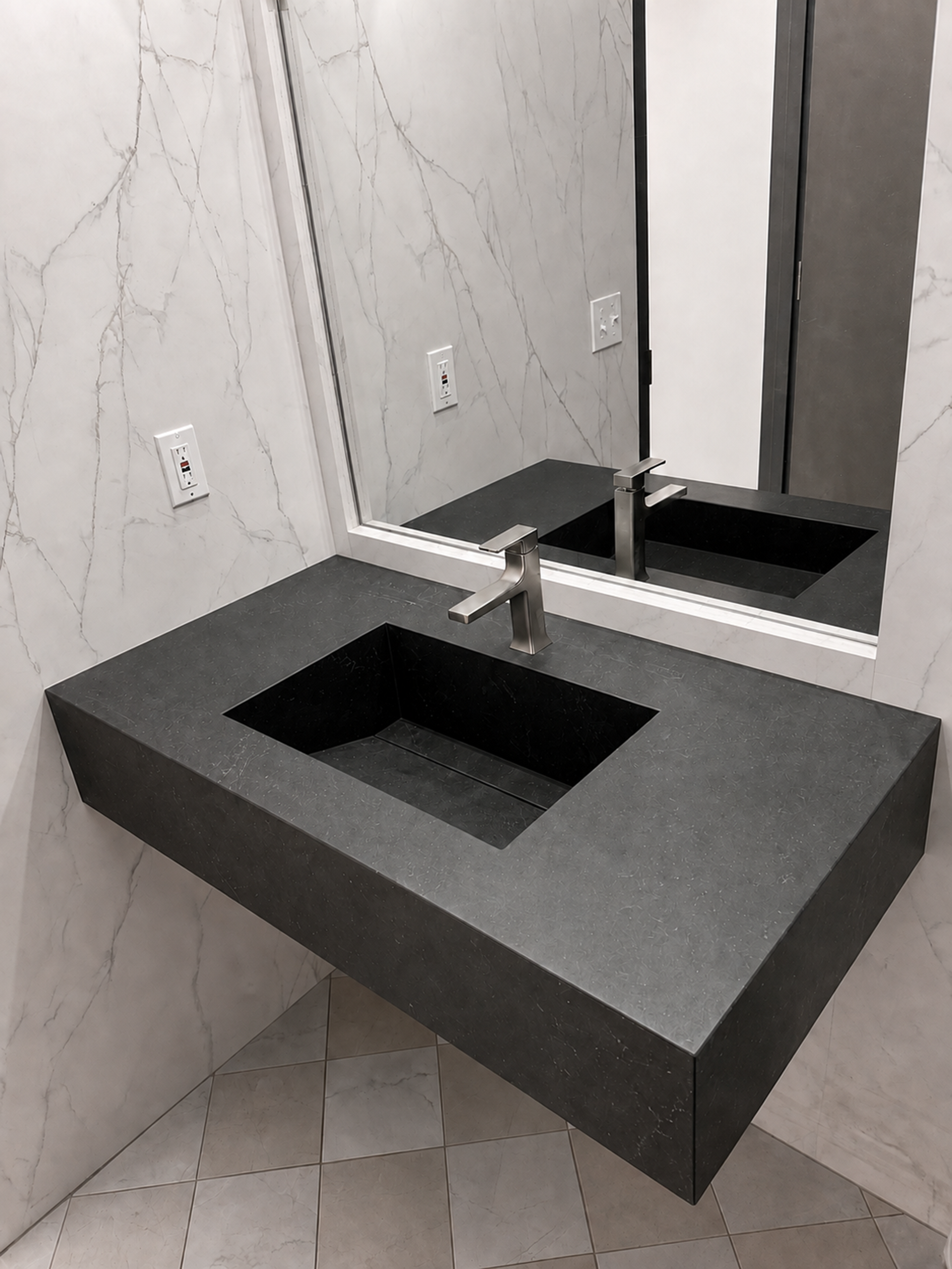 Modern bathroom vanity with floating dark countertop, square sink, and large mirror.