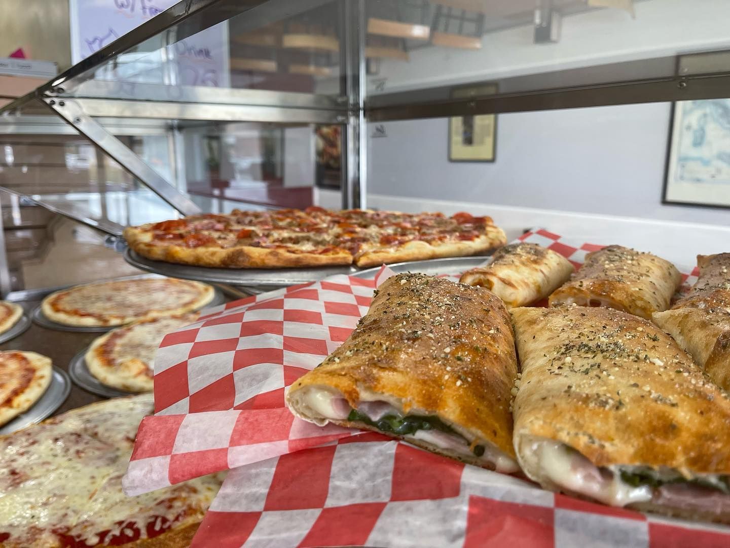 A variety of pizzas and sandwiches are on display in a restaurant.