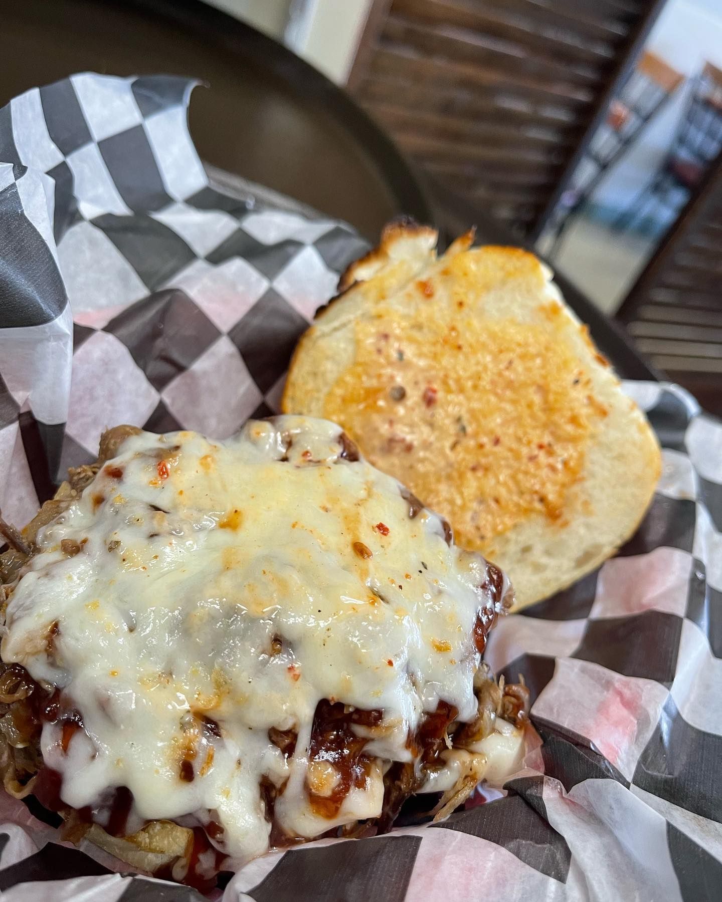 A close up of a sandwich on a checkered paper on a table.