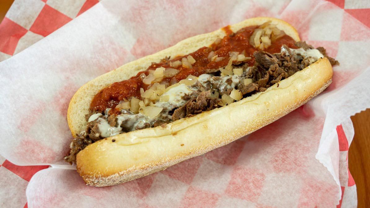 A sub sandwich is sitting on a checkered paper on a table.