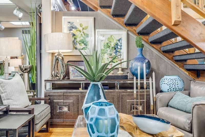 Cozy living room with modern decor, staircase, gray sofa, and blue ceramic vases on a wooden floor.
