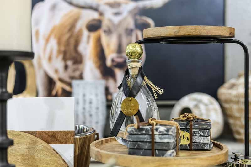 Dog figurine with gold accents on a wooden tray beside wrapped treats and a mug