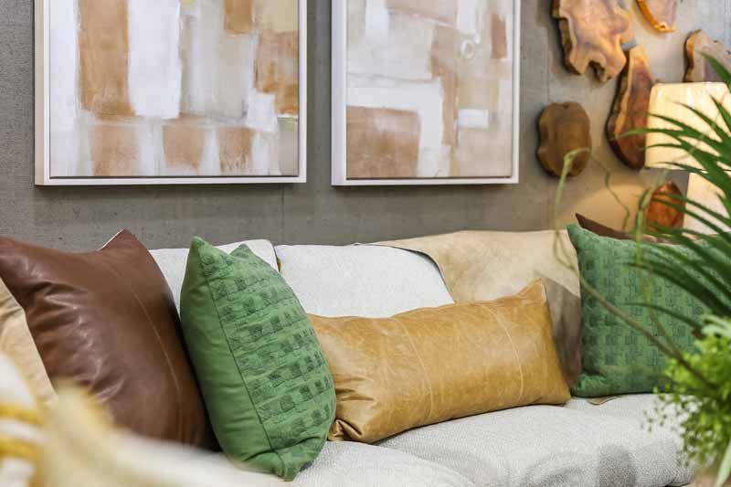 Cozy living room couch with brown, green and gold pillows beneath abstract wall art