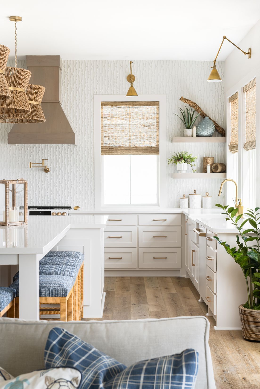 Bright white modern kitchen with wood accents, open shelving, and blue plaid pillows in the foreground