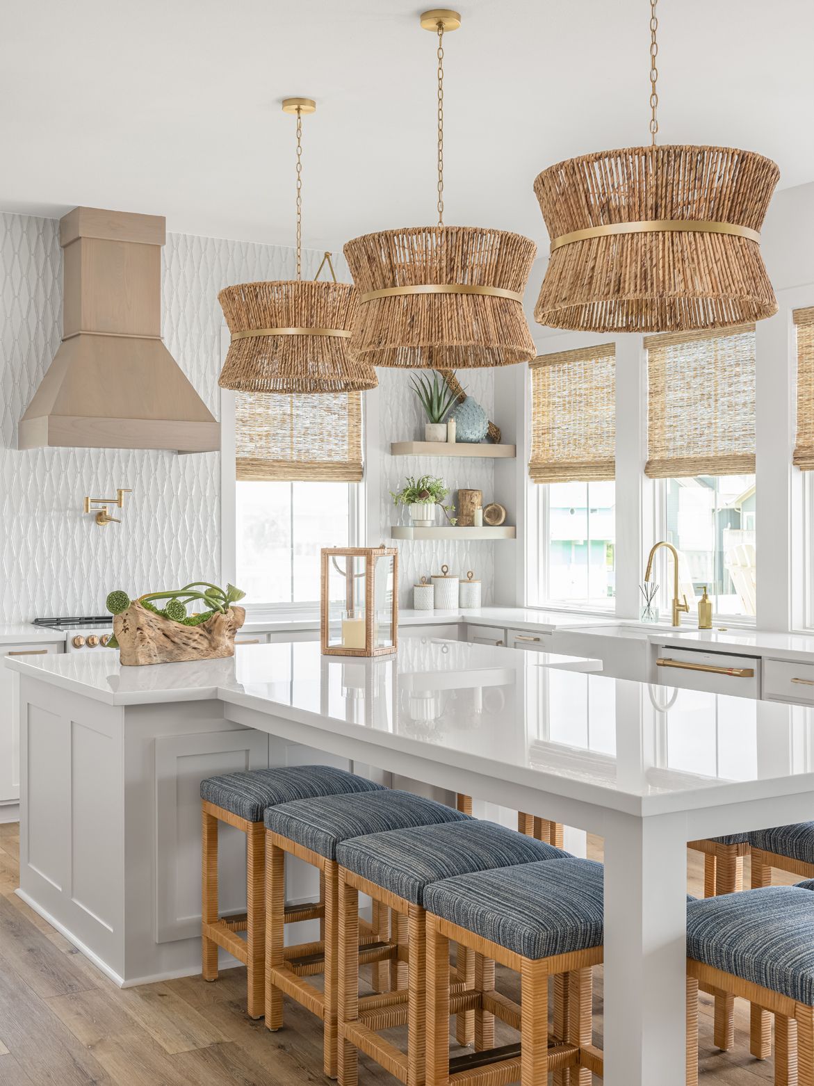 Bright modern kitchen with a large island, wicker pendant lights, and blue-cushioned stools
