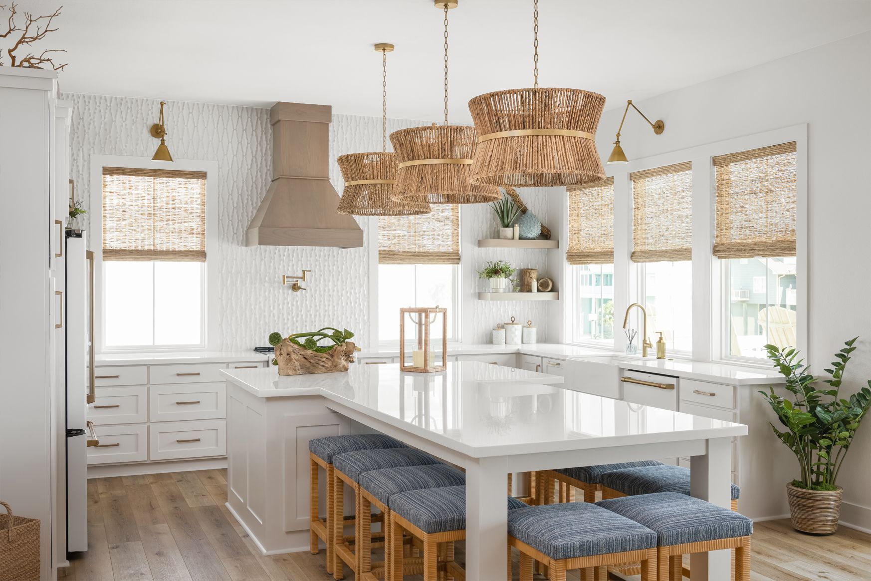 Bright modern kitchen with white cabinets, woven pendant lights, island, and blue stools