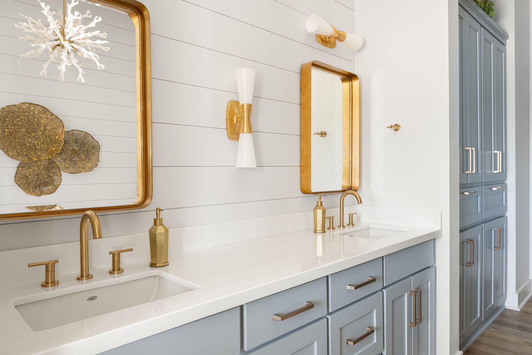 Elegant bathroom with blue-gray vanity, gold fixtures, white shiplap walls, and a large mirror