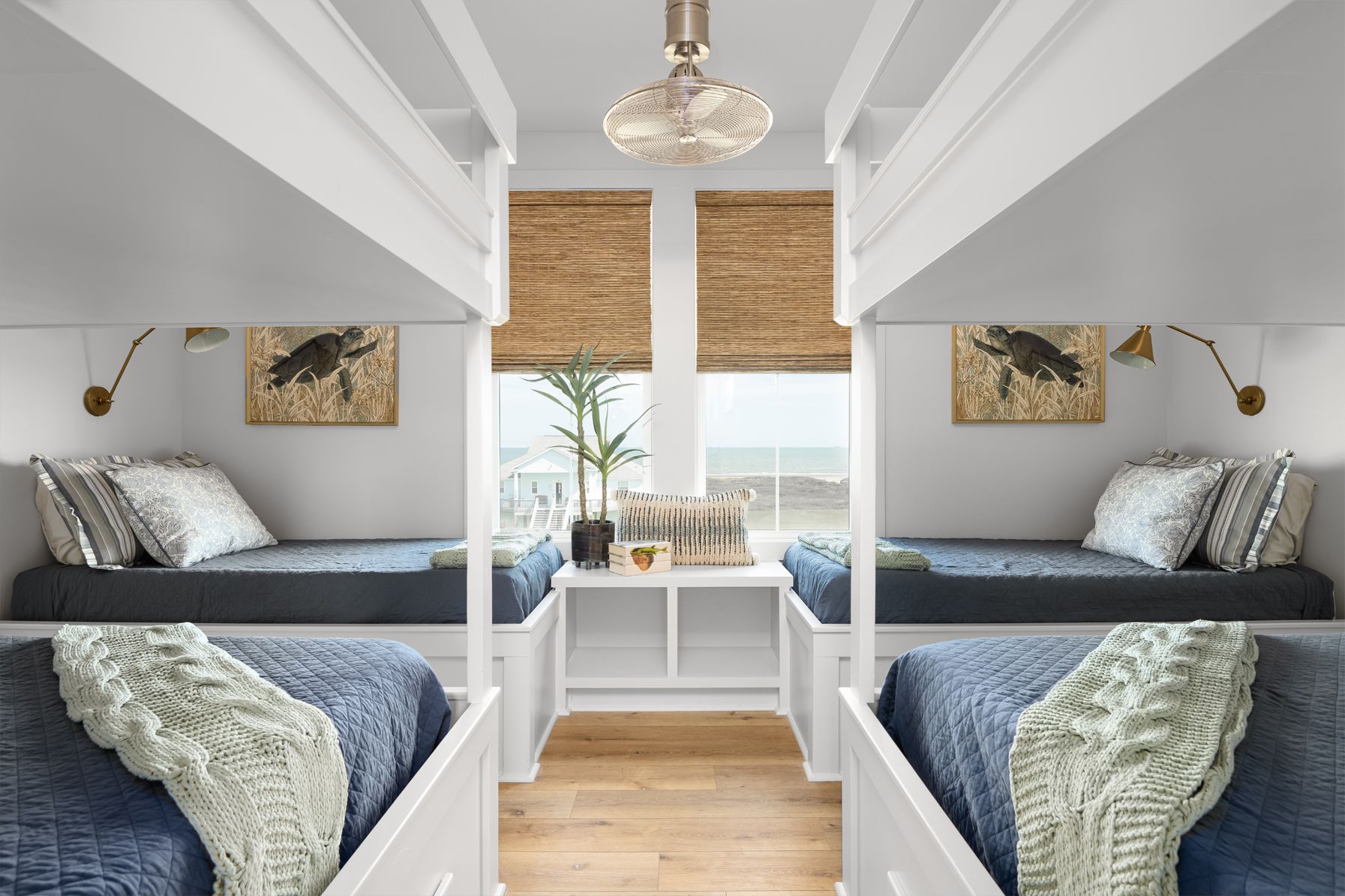Bright bedroom with twin beds, white beams, bamboo shades, and a window seat overlooking greenery