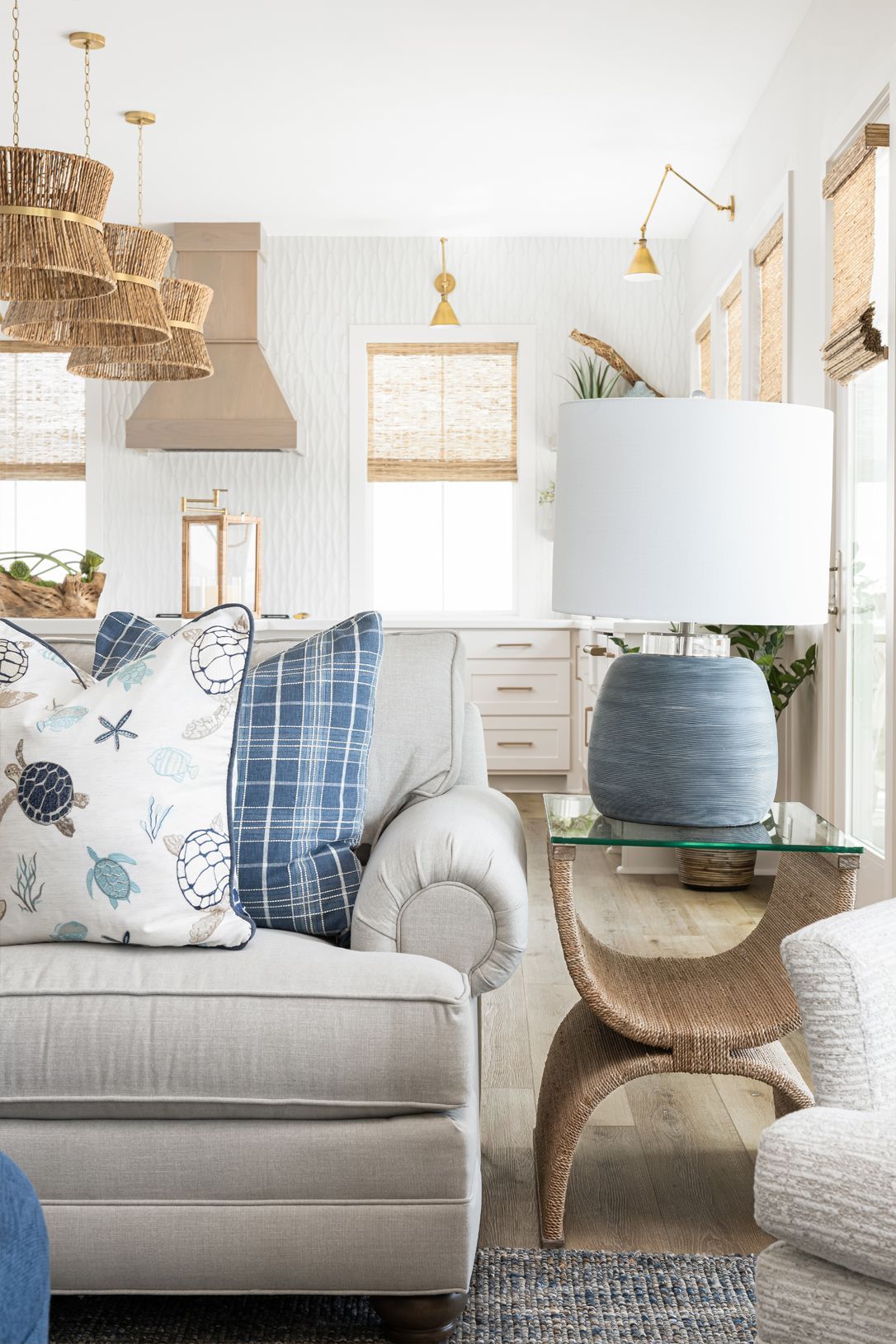 Bright, cozy living room with a beige sofa, patterned pillows, woven lamp, and light wood accents