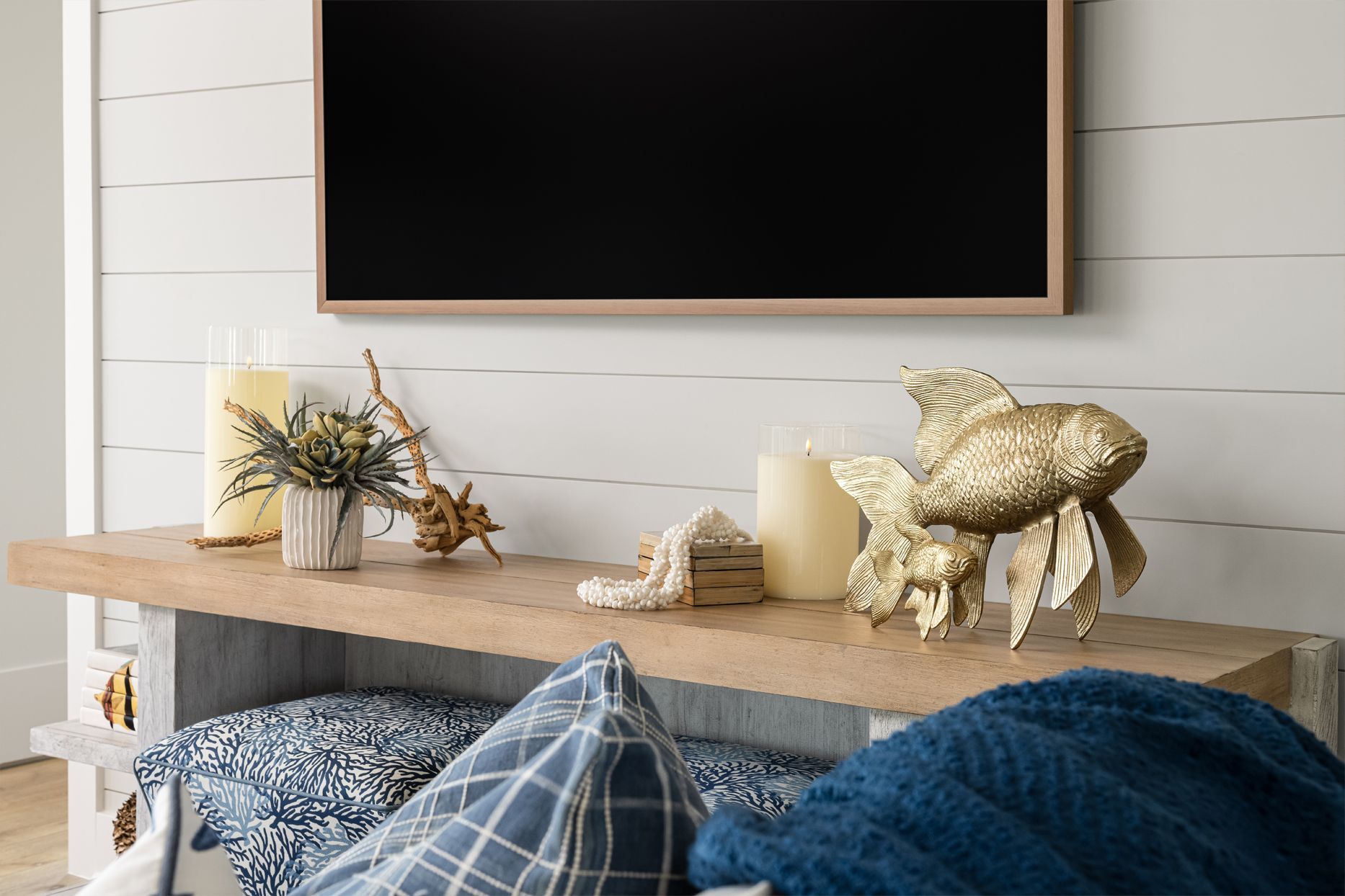 Cozy living room mantel with TV, candles, flowers, and gold deer decor above patterned pillows