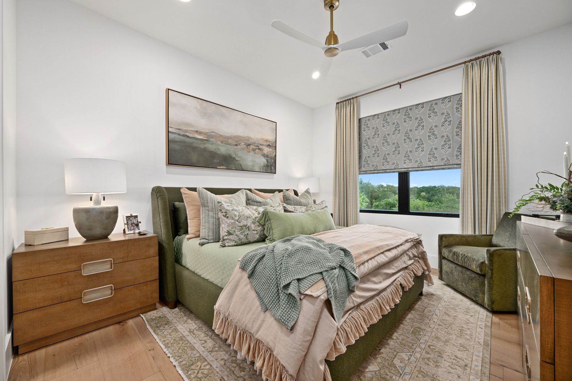 Modern bedroom with a tufted bed, layered pillows, blue accents, and matching bedside lamps