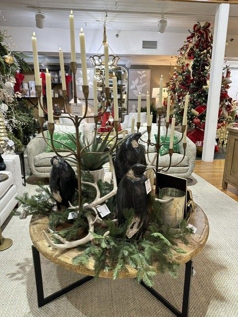 Holiday table centerpiece with candles, evergreen garland, and small black figurines in a decorated store display