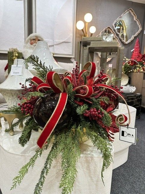 Holiday floral arrangement with red ribbon, pine greenery, and white accents on a table display